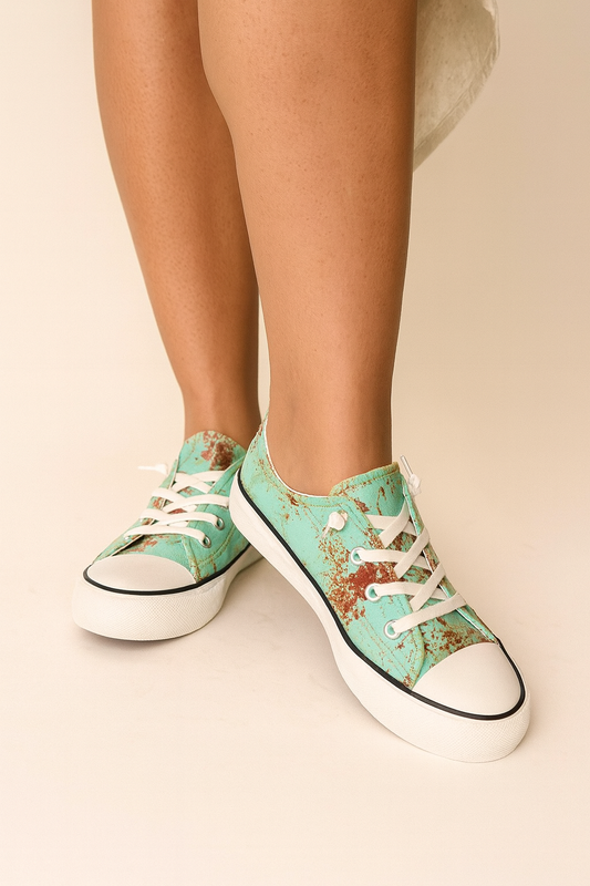 Teal sneakers with white laces worn by a person on a beige background