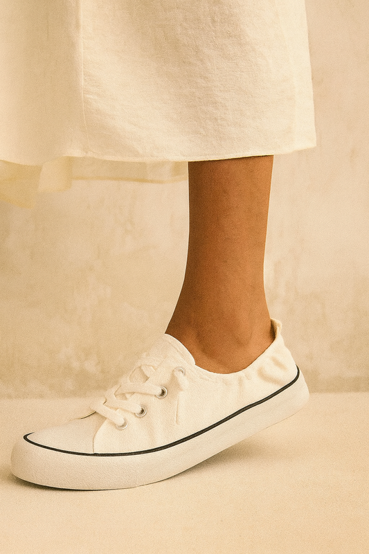 White sneakers with black accents worn with a light-colored skirt on a neutral background