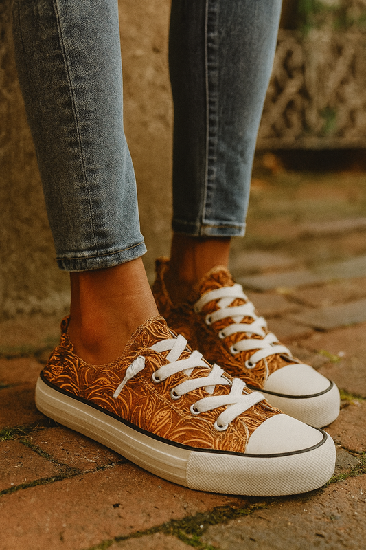 Brown patterned sneakers with white laces worn on a brick surface.